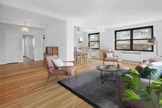 living area featuring radiator heating unit, baseboards, and light wood finished floors