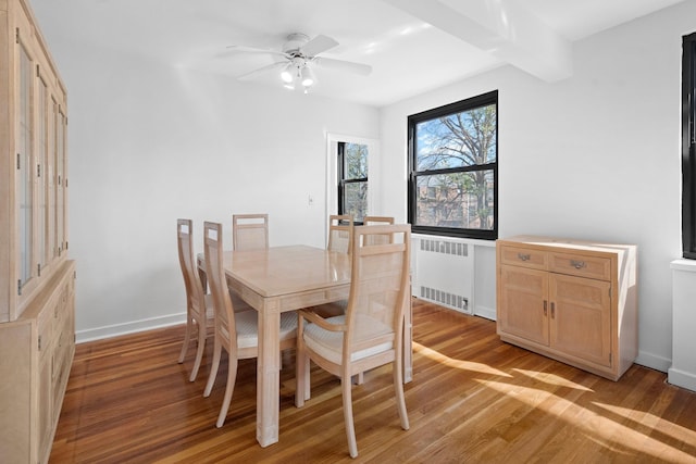 dining room featuring beam ceiling, a ceiling fan, light wood-style floors, radiator, and baseboards