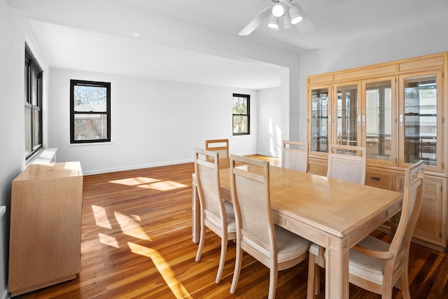 dining space featuring wood finished floors, baseboards, and ceiling fan