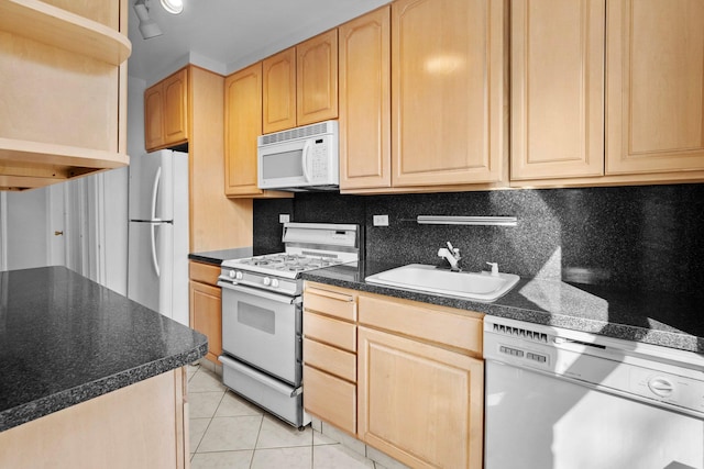 kitchen with light brown cabinetry, white appliances, and a sink