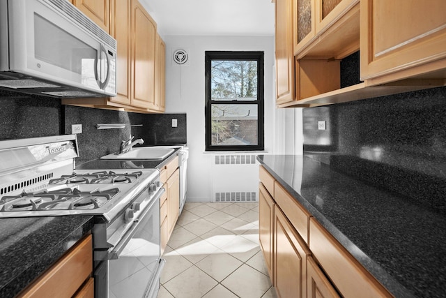 kitchen with a sink, tasteful backsplash, radiator heating unit, gas stove, and white microwave