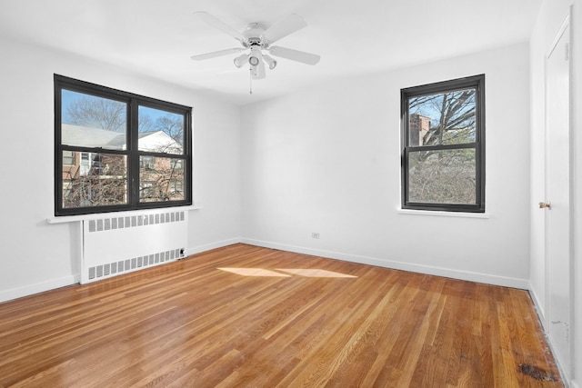 unfurnished room featuring baseboards, radiator, and wood finished floors