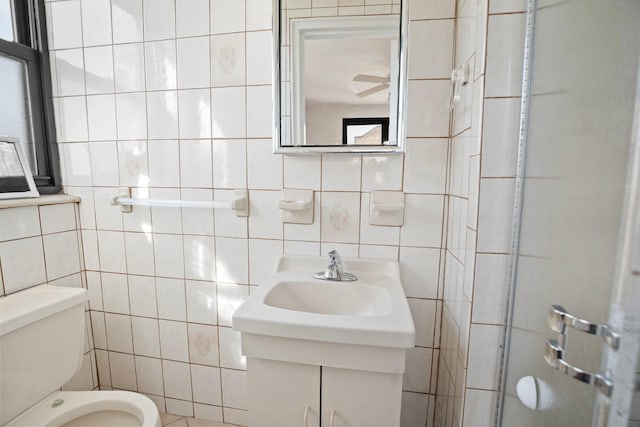 bathroom with toilet, tile walls, a ceiling fan, and a sink