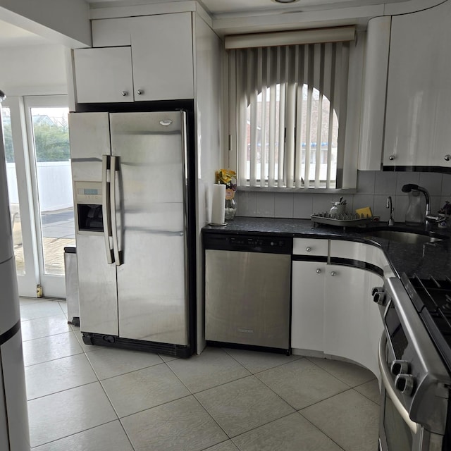 kitchen with light tile patterned floors, stainless steel appliances, tasteful backsplash, white cabinets, and a sink