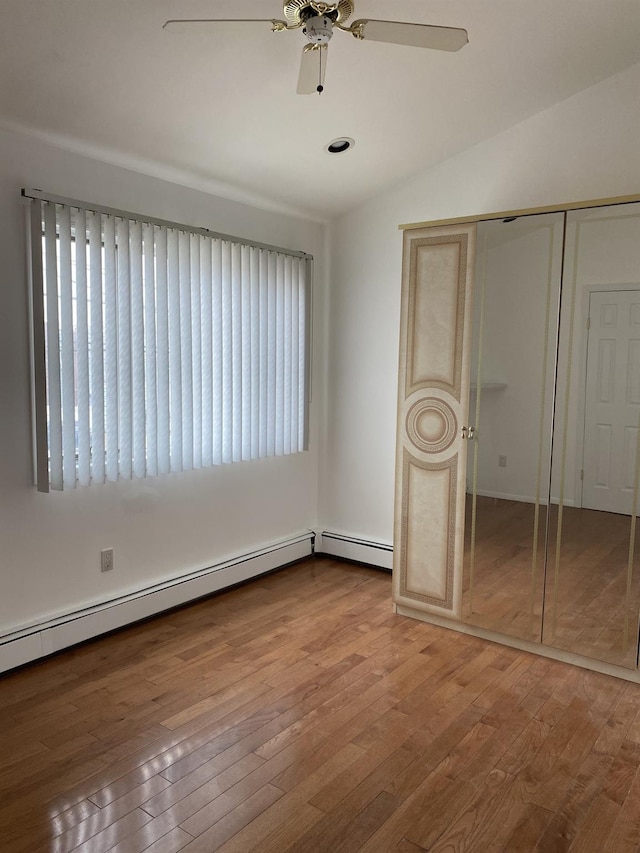 unfurnished bedroom featuring lofted ceiling, hardwood / wood-style flooring, multiple windows, and a closet