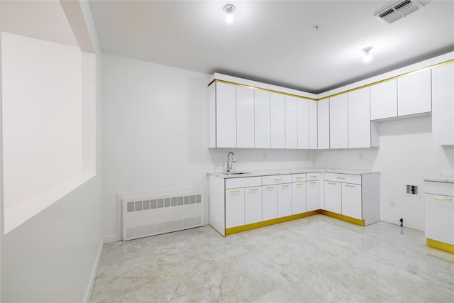 kitchen with visible vents, radiator heating unit, light countertops, white cabinetry, and a sink