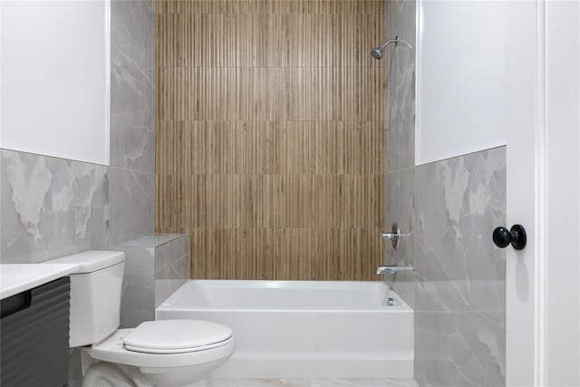 bathroom featuring tile walls, toilet, vanity, and shower / bathing tub combination