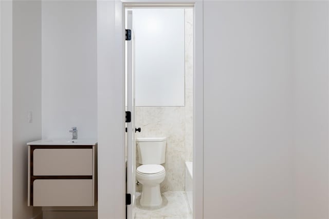 full bathroom featuring vanity, tile walls, toilet, and a tub