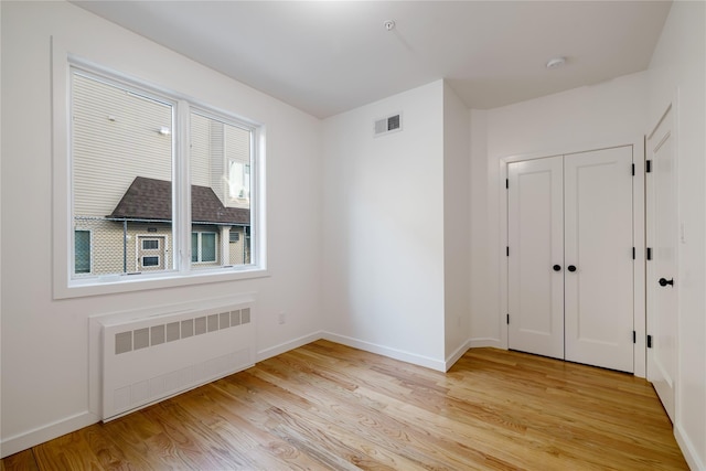 interior space featuring visible vents, baseboards, radiator, and light wood finished floors