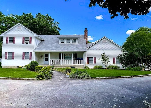 view of front of property featuring a porch, a front yard, a shingled roof, and a chimney