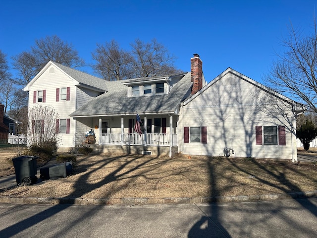 view of front of house with covered porch, roof with shingles, a front lawn, and a chimney