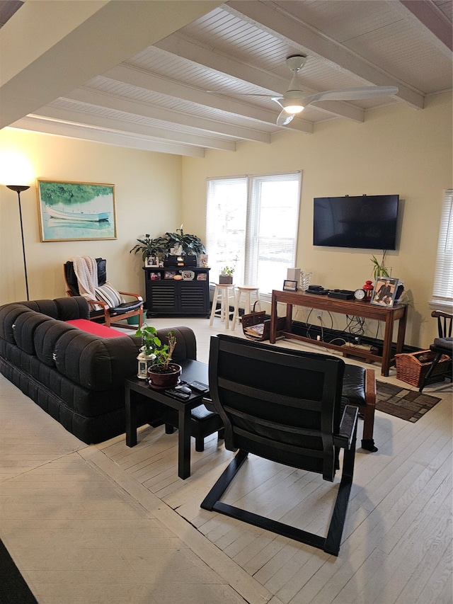 living area with a ceiling fan, beamed ceiling, and hardwood / wood-style floors