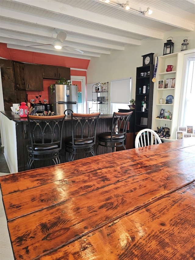 dining space featuring ceiling fan and beamed ceiling