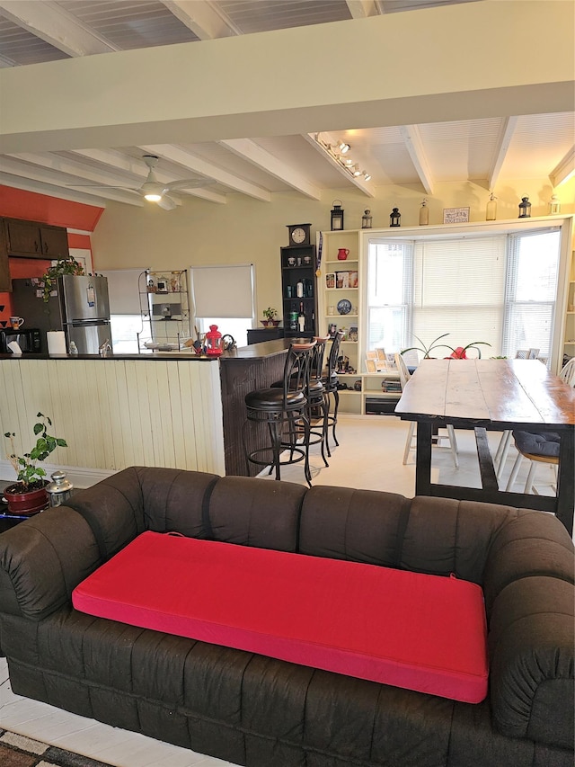 living area with a ceiling fan and beam ceiling