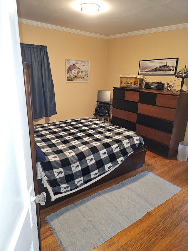 bedroom with wood finished floors and crown molding