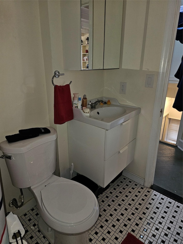 half bath with tile patterned flooring, vanity, and toilet