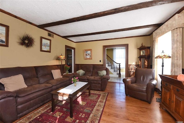 living room with a textured ceiling, wood finished floors, visible vents, stairs, and beam ceiling