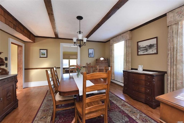 dining room with baseboards, an inviting chandelier, beam ceiling, and light wood-style floors