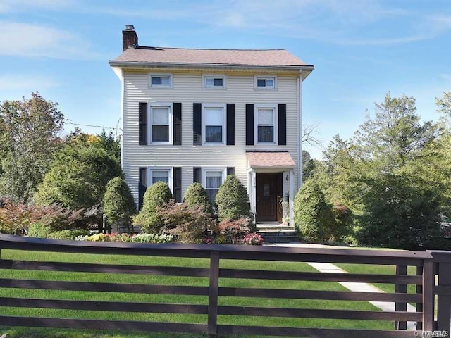 view of front of property with fence, a chimney, and a front lawn