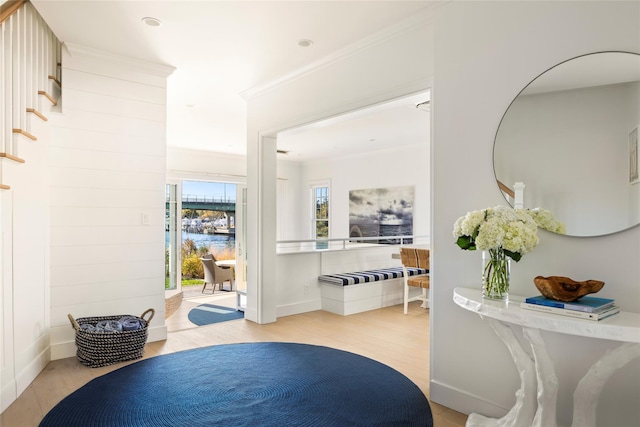 hall with a water view, stairway, ornamental molding, light wood-type flooring, and baseboards