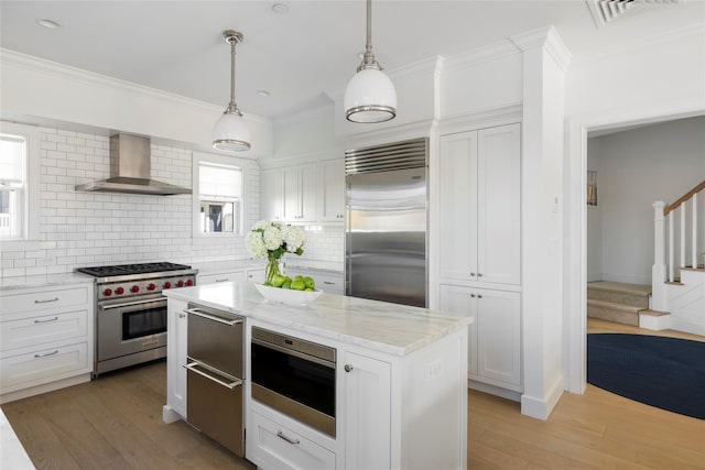 kitchen with visible vents, wall chimney exhaust hood, ornamental molding, and high quality appliances