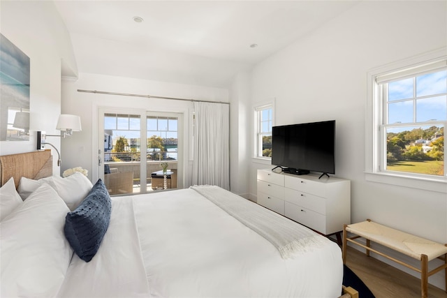 bedroom featuring access to exterior, lofted ceiling, and wood finished floors