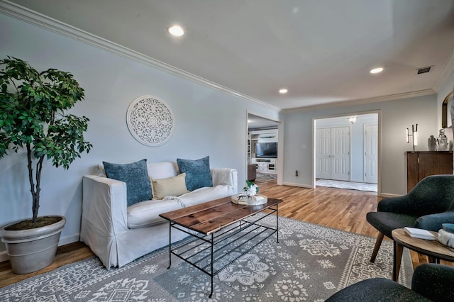 living area featuring visible vents, baseboards, ornamental molding, recessed lighting, and wood finished floors