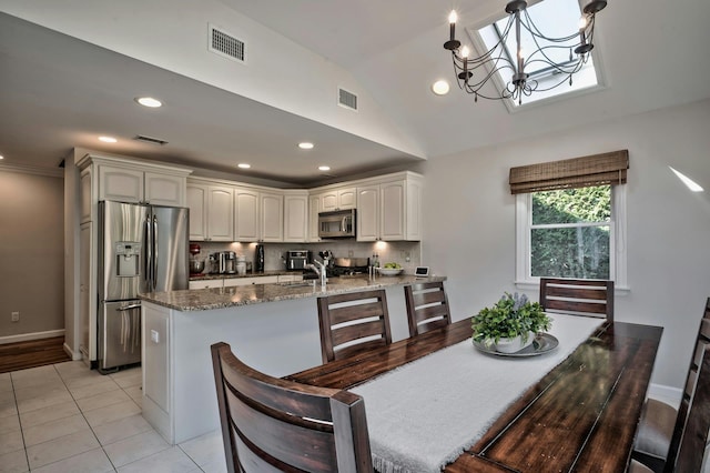 dining room with light tile patterned floors, visible vents, lofted ceiling, and an inviting chandelier