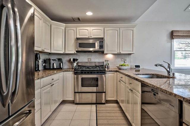 kitchen with visible vents, backsplash, appliances with stainless steel finishes, light tile patterned flooring, and a sink