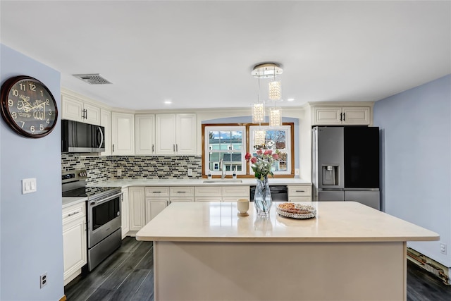 kitchen featuring a sink, light countertops, dark wood-type flooring, appliances with stainless steel finishes, and tasteful backsplash