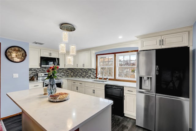 kitchen featuring visible vents, a sink, backsplash, appliances with stainless steel finishes, and light countertops