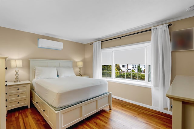 bedroom featuring a wall mounted air conditioner, baseboards, and dark wood finished floors