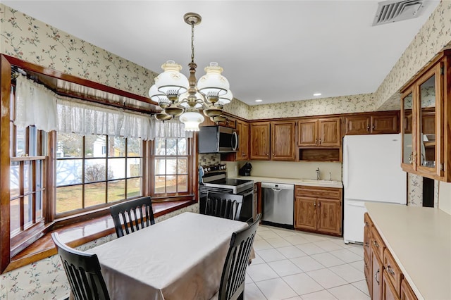 kitchen with visible vents, wallpapered walls, light countertops, stainless steel appliances, and a sink