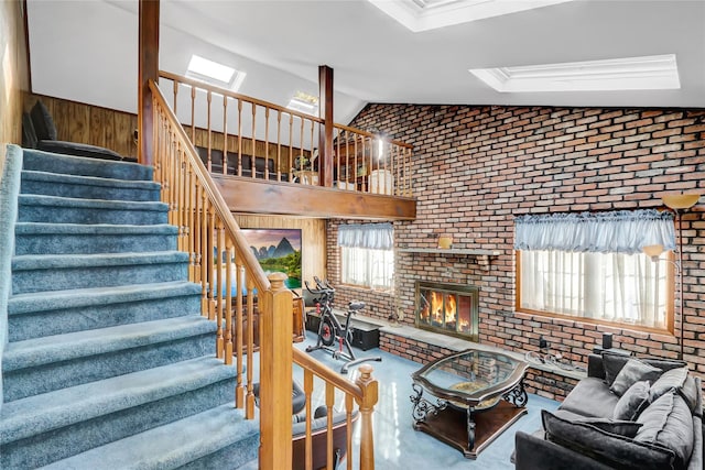 living room featuring a healthy amount of sunlight, brick wall, a fireplace, and vaulted ceiling