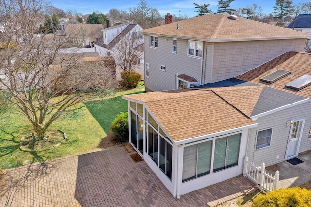 back of property featuring a patio, a yard, a sunroom, and roof with shingles