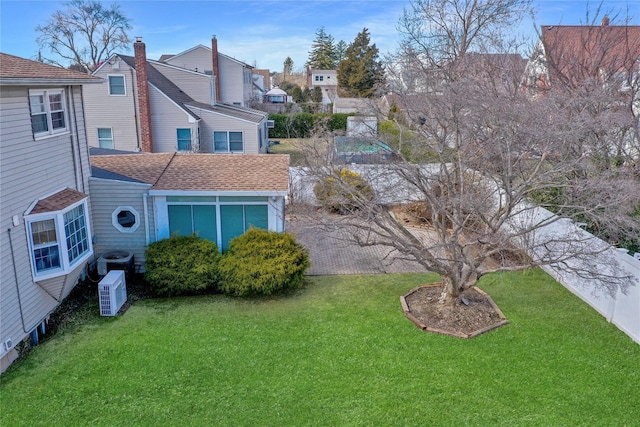 back of property featuring a lawn, cooling unit, and a shingled roof