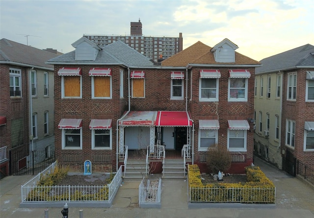 view of front of home featuring a shingled roof and brick siding