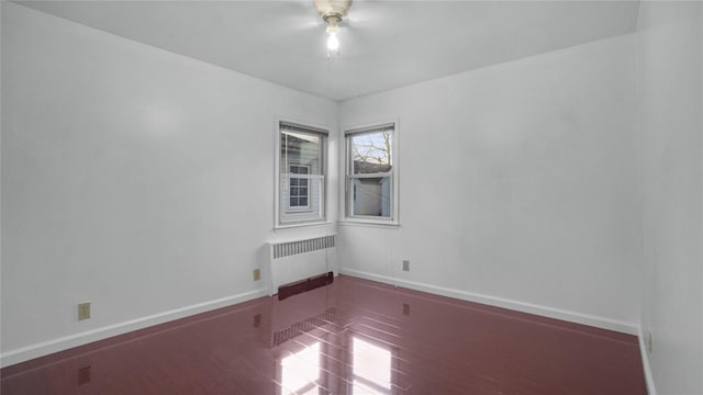 spare room with radiator heating unit and baseboards