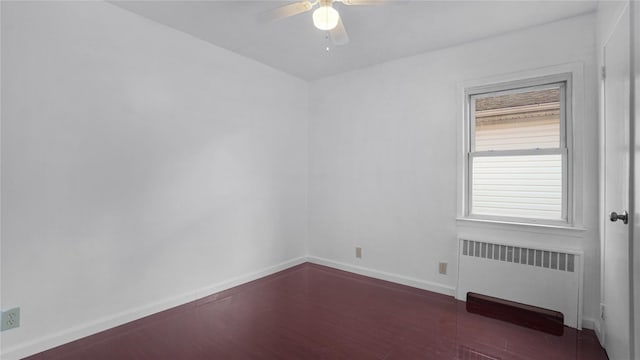 spare room featuring baseboards, a ceiling fan, and radiator