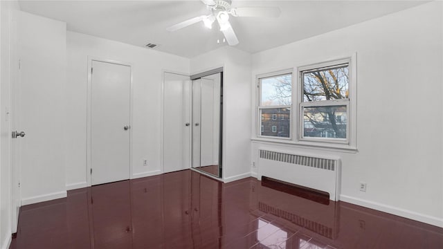 unfurnished bedroom featuring ceiling fan, radiator heating unit, visible vents, and baseboards