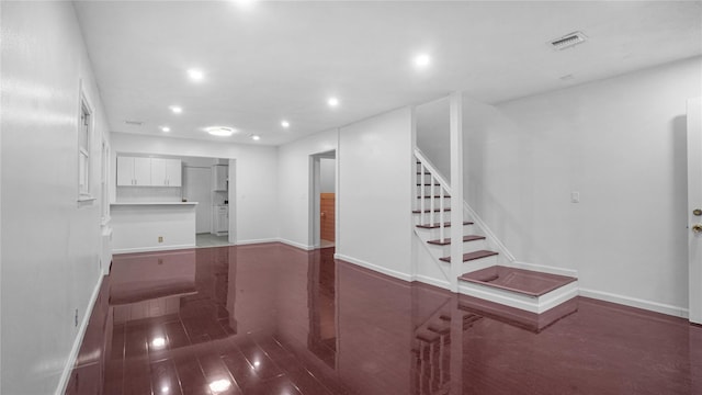 unfurnished living room with recessed lighting, wood finished floors, visible vents, baseboards, and stairway