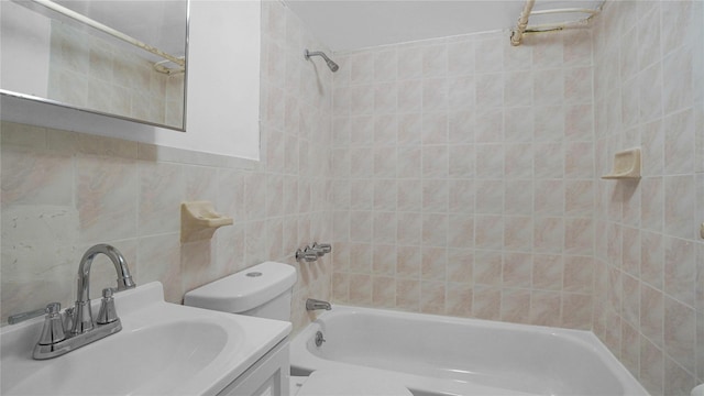 bathroom with toilet, vanity, tile walls, and shower / bathtub combination