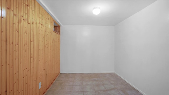 unfurnished room featuring wood walls and baseboards