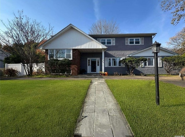 view of front facade featuring fence, a front lawn, and brick siding