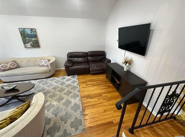 living area with lofted ceiling, stairway, and wood finished floors