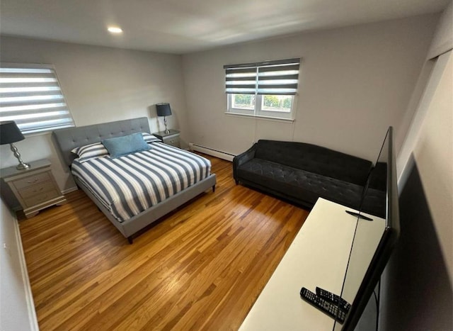 bedroom with baseboard heating, wood finished floors, and recessed lighting