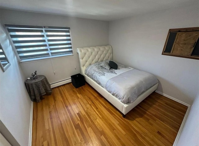 bedroom with baseboards, light wood-style flooring, and baseboard heating