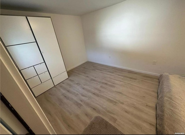 unfurnished bedroom with a closet, wood finished floors, and baseboards