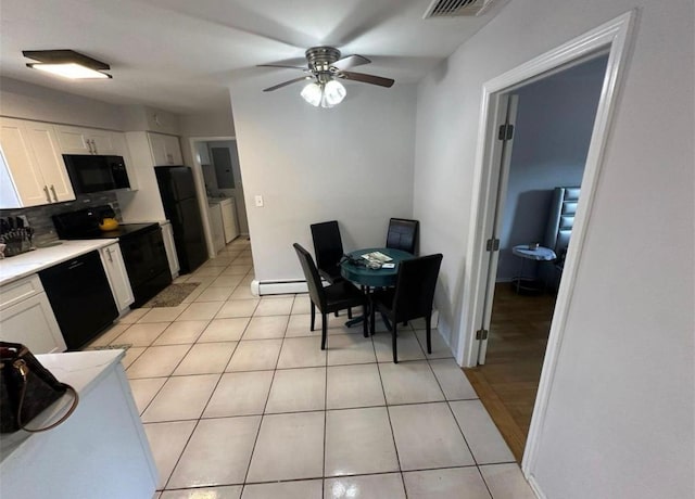 kitchen with light tile patterned floors, white cabinets, light countertops, baseboard heating, and black appliances