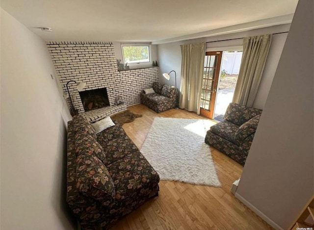 living area with a brick fireplace, brick wall, baseboards, and wood finished floors